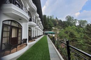a building with a green lawn next to a fence at Entranceway Resort in Mussoorie