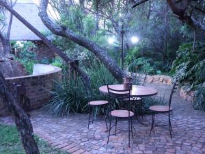 einen Tisch und Stühle auf einer Terrasse unter einem Baum in der Unterkunft Monkey Thorn in Roodeplaat