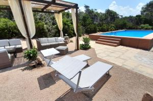 un patio con sillas blancas y una piscina en Ferienhaus Casa Sole - Villaggio Galanu, en Li Valcaggi