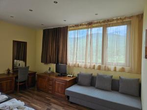 a living room with a couch and a desk with a computer at Family Hotel Komhotel in Berkovitsa