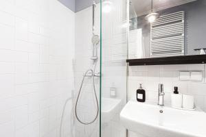 a white bathroom with a shower and a sink at Komfortowy apartament w samym centrum Wrocławia in Wrocław