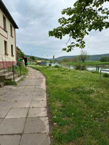 a sidewalk next to a building and a river at Haus an der Weser in Oedelsheim