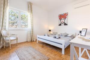 a white bedroom with a bed and a chair at Apartment Kosljun with pool in Košljun