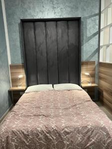 una camera con un grande letto con testiera nera di Stresa Court Apartments a San Giuliano
