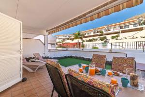 een tafel en stoelen op een balkon met sinaasappelsap bij Los Cristianos El Mirador - As de Casas in Los Cristianos