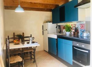 una cocina con armarios azules y una mesa. en La Petite Grange, pour un séjour écolo-chic !, en Lachapelle-sous-Aubenas