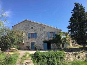 una casa de piedra con puertas azules en una colina en La Petite Grange, pour un séjour écolo-chic ! en Lachapelle Sous Aubenas