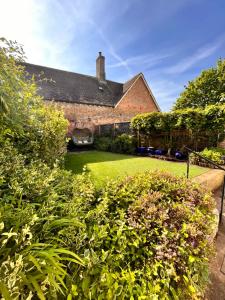 an old brick house with a green yard at The Snuggery Cottage in Taunton