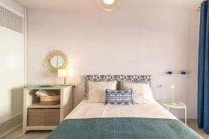 een slaapkamer met een bed en een spiegel en blauwe gordijnen bij Los Cristianos El Mirador - As de Casas in Los Cristianos +35 foto's