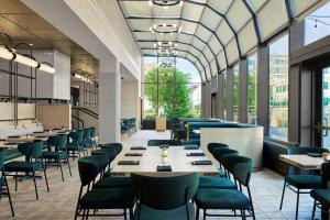 un restaurante con sillas verdes, mesas y ventanas en Delta Hotels by Marriott Muskegon Convention Center, en Muskegon