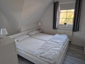 a white bed in a room with a window at Köster, Birgit FW 5 in Zingst