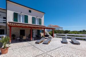 a group of lounge chairs on a patio next to a building at Apartment Kosljun with pool in Košljun