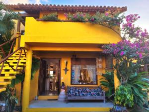 a yellow house with a bench in front of it at Guest House Villa 2 Santos in Arraial d'Ajuda