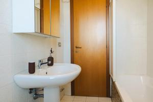 Łazienka z białą umywalką i drewnianymi drzwiami w obiekcie Alessandrino Apartment w Rzymie