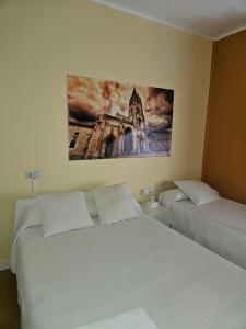 um quarto com duas camas e um quadro na parede em El Vasco Rooms em Oviedo