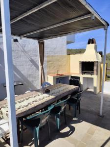 een tafel en stoelen op een patio met een pizza-oven bij Casa Villazo II in Almáchar