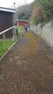 a person walking down a path next to a wall at Springside Chalet20 in Tywyn