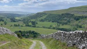 a dirt road on a hill with a stone wall at Dale House in Kettlewell