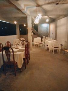 uma sala de jantar com mesas brancas e cadeiras brancas em Hotel Pinnacle em Palampur