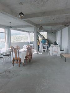 uma sala de jantar com mesas e cadeiras brancas e pessoas em Hotel Pinnacle em Palampur