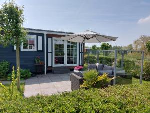 una casa y un patio con sombrilla y sillas en Schelde vakantie chalet, en Baarland