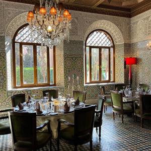 ein Esszimmer mit Tischen, Stühlen und einem Kronleuchter in der Unterkunft The Red House in Marrakesch