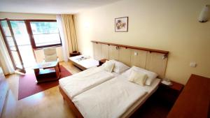 a bedroom with a large white bed and a window at Hotel Ambra in Luhačovice