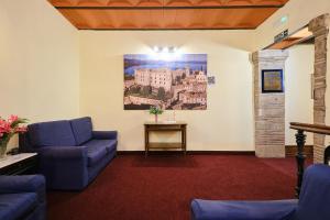 a living room with blue couches and a painting on the wall at Albergo Della Posta in Bracciano