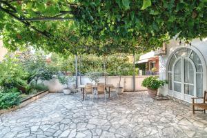 een patio met een tafel en stoelen onder een boom bij Sun Guest House in Budva