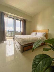 um quarto com uma cama e uma grande janela em QFandZ Baguio Homestay at BRENTHILL Condominium em Baguio