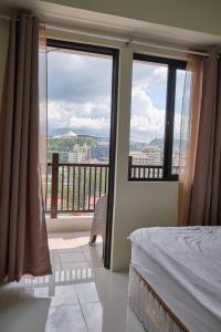 1 dormitorio con 1 cama y 2 ventanas con vistas en QFandZ Baguio Homestay at BRENTHILL Condominium en Baguio