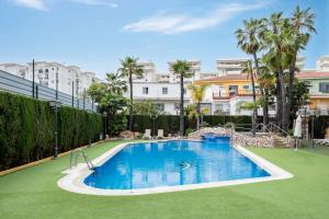 a swimming pool in a resort with palm trees and buildings at Boliches Mediterraneo Real Tropical Coast by Alfresco Stays in Las Lagunas Mijas