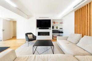 a white living room with a couch and a tv at Rosario Pool Villa in Cascais