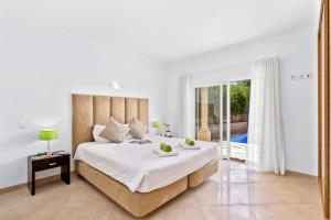 een witte slaapkamer met een groot bed en een balkon bij Villa Helene Norvilla - Luxury villa walkable to shops, restaurants, heated pool, close to Gale beach in Guia