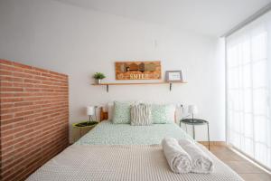 ein Schlafzimmer mit einem Bett und einer Ziegelwand in der Unterkunft CHIC APARTAMENTS in Tossa de Mar