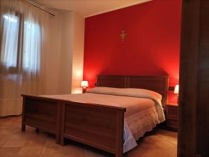 - une chambre dotée d'un lit avec un mur rouge dans l'établissement Il Melograno, à Torino di Sangro