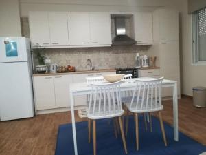 a kitchen with white cabinets and a white table and chairs at Garden in Almirón +20 photos