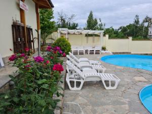 a group of white lounge chairs next to a swimming pool at Family Hotel Komhotel in Berkovitsa