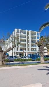 un grande edificio bianco con auto parcheggiate in un parcheggio di Appartamenti Vacanze Vista mare ad Alba Adriatica