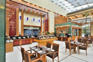 a restaurant with tables and chairs and a kitchen at Ramada By Wyndham Jaipur in Jaipur