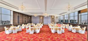 une salle de banquet avec des tables, des chaises et des lustres dans l'établissement Ramada By Wyndham Jaipur, à Jaipur