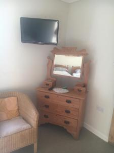 a bedroom with a dresser with a mirror and a chair at Fferm Glanyrynys Farm in Carmarthen