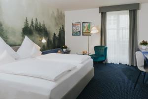 a hotel room with a white bed and a green chair at Gutshof Sagmühle in Bad Griesbach +57 photos