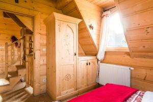 sypialnia w drewnianym domku z czerwonym łóżkiem w obiekcie TatryTop Osada Luxury Chalets Kościelisko w mieście Kościelisko +37 zdjęć
