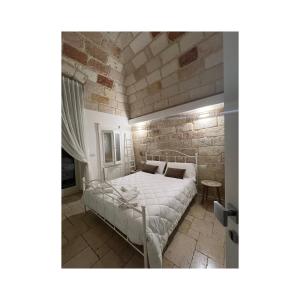 a bedroom with a bed and a brick wall at Locus Amoenus in Polignano a Mare