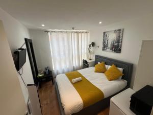 um pequeno quarto com uma cama com almofadas amarelas em Canary Wharf O2 Arena Excel London em Londres