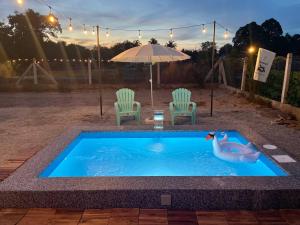 a swimming pool with two chairs and a swan in it at Tiny House & Pool 4 pax 3 mins Merang Jetty in Setiu