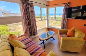 ein Wohnzimmer mit einem Sofa, einem Tisch und Fenstern in der Unterkunft Maison de la Lagune in Oualidia