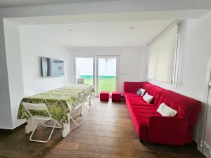 a living room with a red couch and a table at Casa del Arenal - Laxe in Laxe