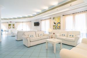 een grote woonkamer met witte meubels en ramen bij Cala Della Torre Resort in La Caletta